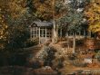 Beautiful fall scene of a cozy cottage surrounded by colorful autumn trees by a tranquil lake.